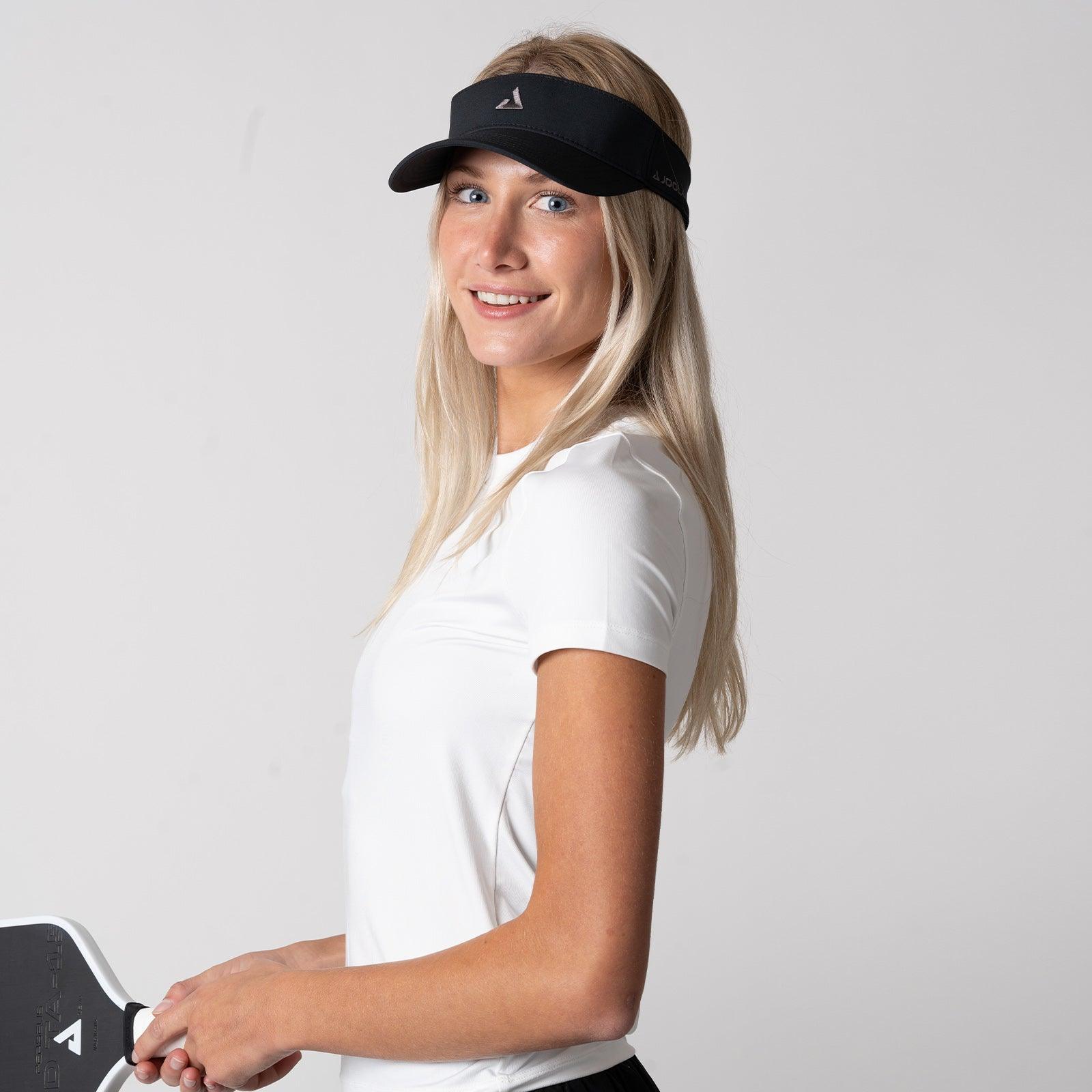 Frau mit schwarzem Sport-Visor und weißem T-Shirt hält einen schwarzen Pickleball-Schläger.